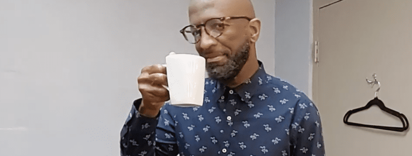 Man in glasses holding a white mug.